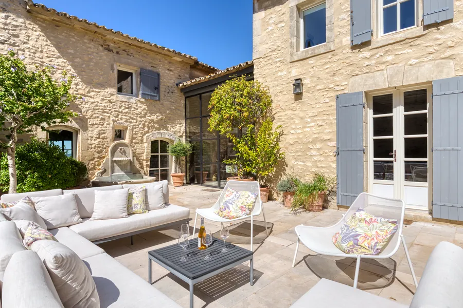 The stone courtyard with fountain, blue-grey shutters and deep outdoor sofas