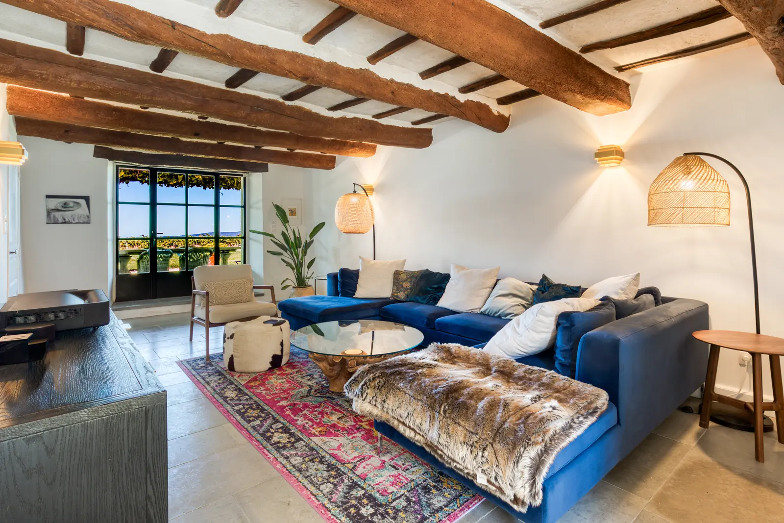 The den: a deep blue sectional, antique rug and old oak beams, with vineyard views