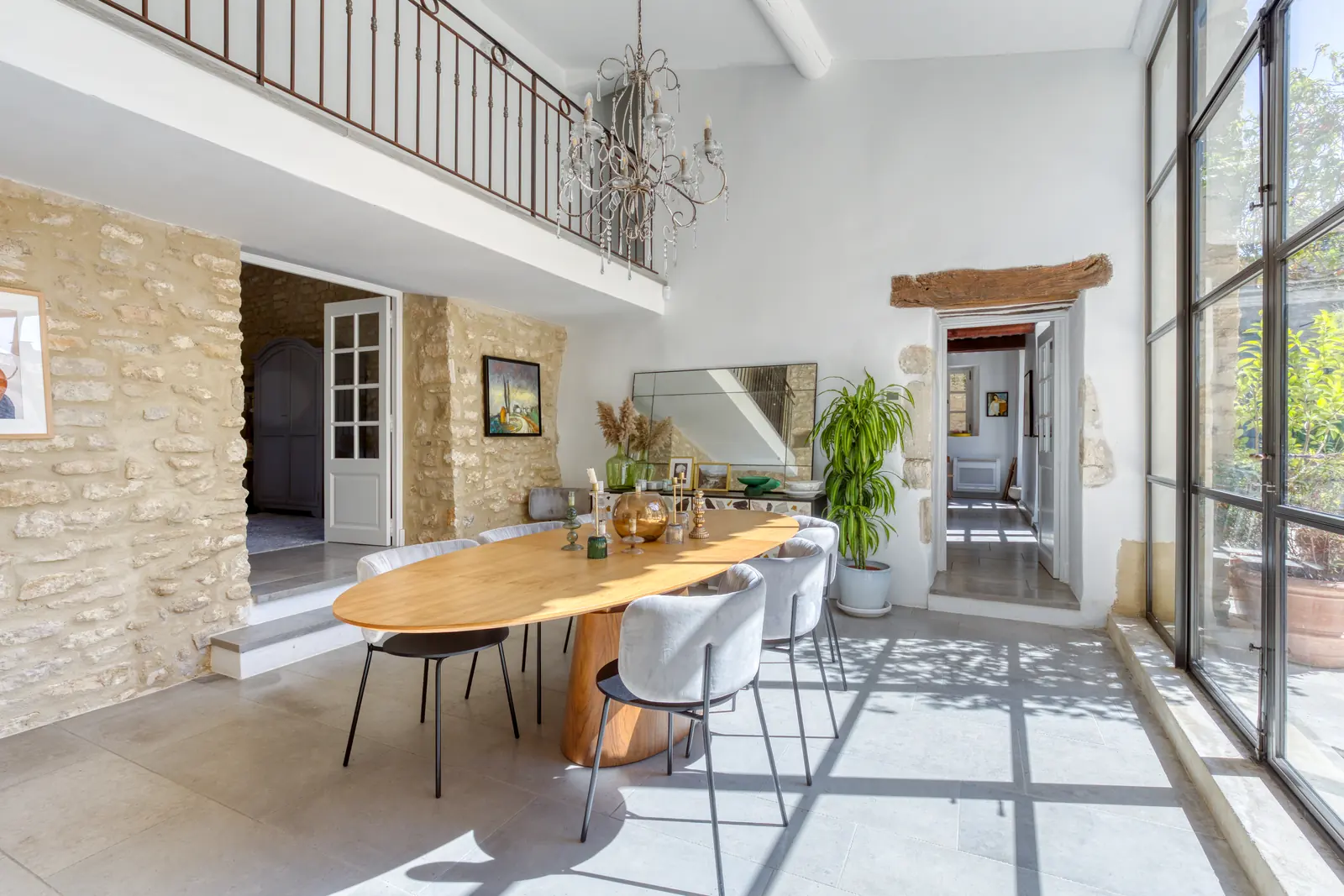 A double-height dining hall with steel-framed windows, stone walls and an oval table for eight