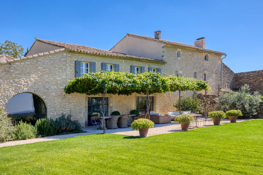 The stone façade with its vine pergola, arched doorway and blue-grey shutters