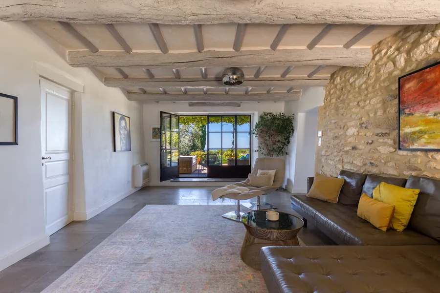 The living room with a leather sectional, stone wall and beamed ceiling