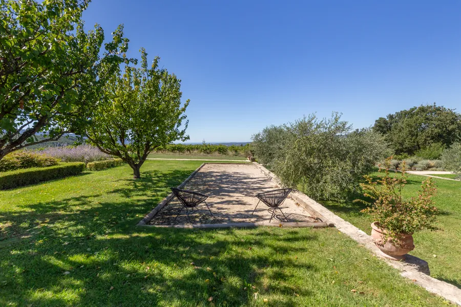 The pétanque court in dappled shade, with the valley beyond