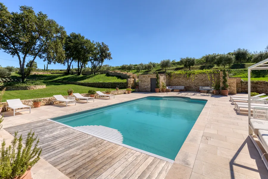 The pool deck with loungers and olive trees on the terraces above