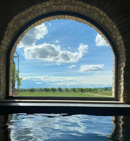 The valley and sky framed by an arched stone window above the indoor pool
